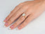 Woman’s hand with eternal halo engagement ring featuring oval diamond and delicate halo