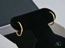 Glimmergold 18k mini hoop earrings: gold oval hoops on black velvet