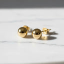 Gold ball stud earrings with a polished finish.