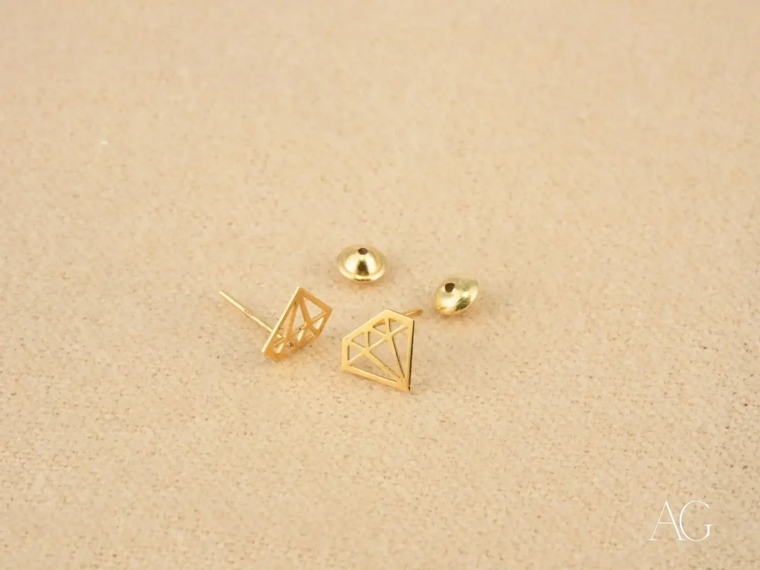 Gold-colored diamond-shaped stud earrings with a geometric wireframe design featured in an article on engagement rings and jewelry as symbols of secret meaning and modern traditions highlight fine jewelry and gold jewelry styles.
