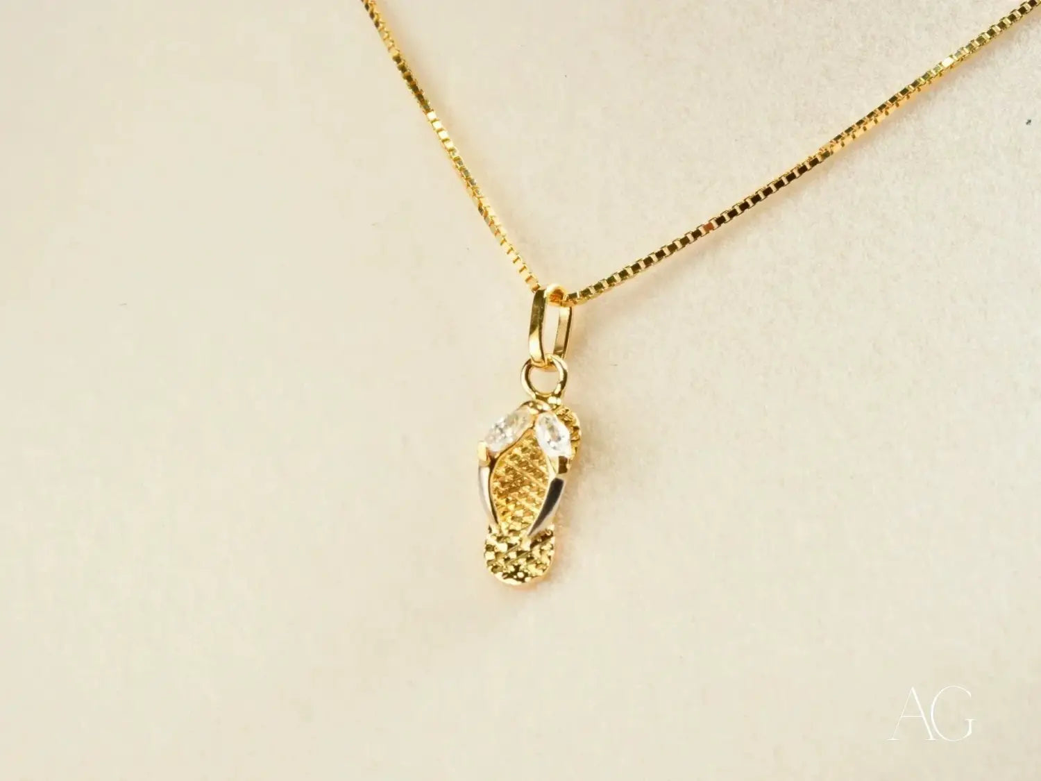 Gold flip-flop pendant necklace in 18k gold with clear crystal accents featured in fine jewelry comparison between Buccellati and De Beers.