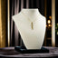 A gold rectangular bar pendant with a single small diamond, suspended from a delicate chain, displayed on an off-white jewelry bust.