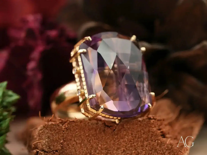 A stunning gold ring featuring a large, faceted purple amethyst stone set in an intricate prong and beaded design.