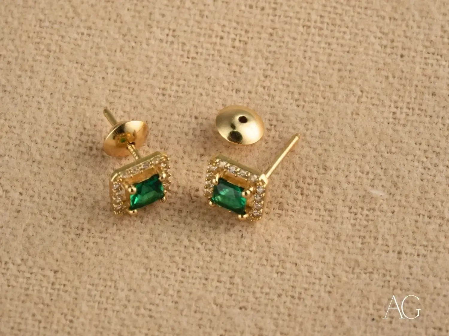 gold stud earrings featuring emerald green square-cut stones surrounded by a halo of tiny clear crystals crafted in 18k gold, exemplifying fine jewelry in the birthstone jewelry inspirations collection.