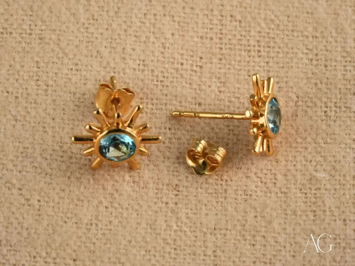 gold sunburst stud earrings featuring a central blue gemstone exemplify luxury jewelry craftsmanship in fine gold jewelry collections.