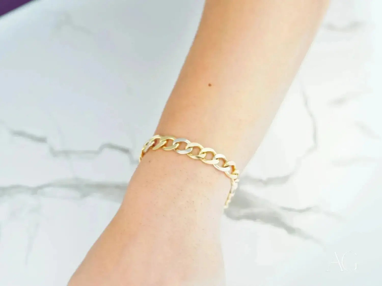 Two gold-toned fine jewelry rings with delicate diamond accents displayed on a cream-colored knitted sweater.