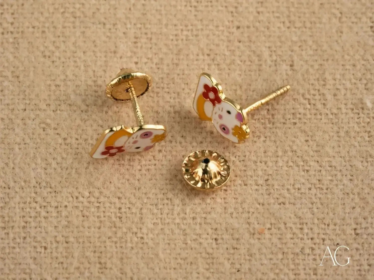 gold-toned hello kitty stud earrings with enamel floral detailing showcasing art gold jewelry style for a listicle on 18k gold trends before visiting everett jewelry store