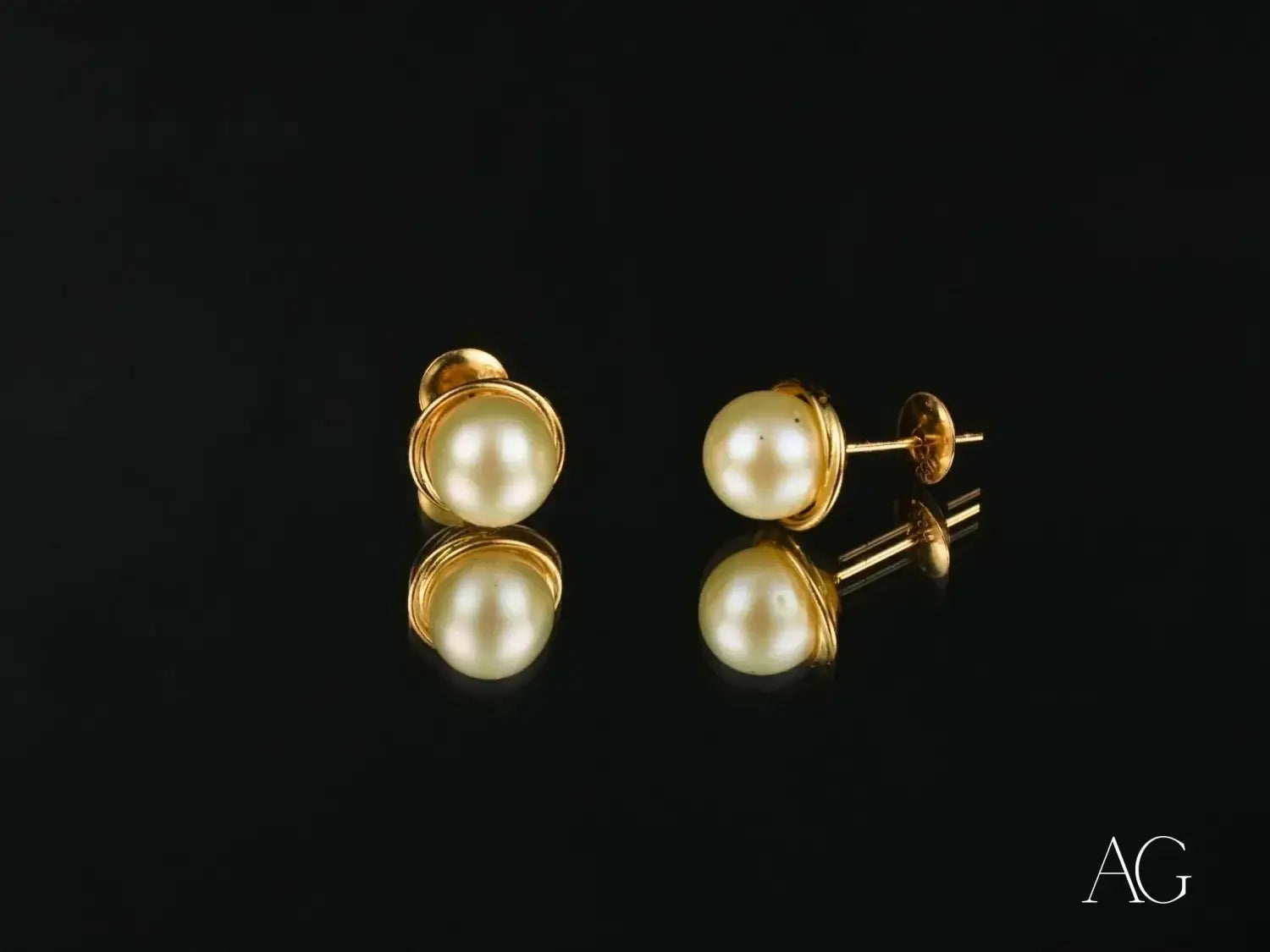 Elegant gold-toned pearl stud earrings in art gold jewelry display