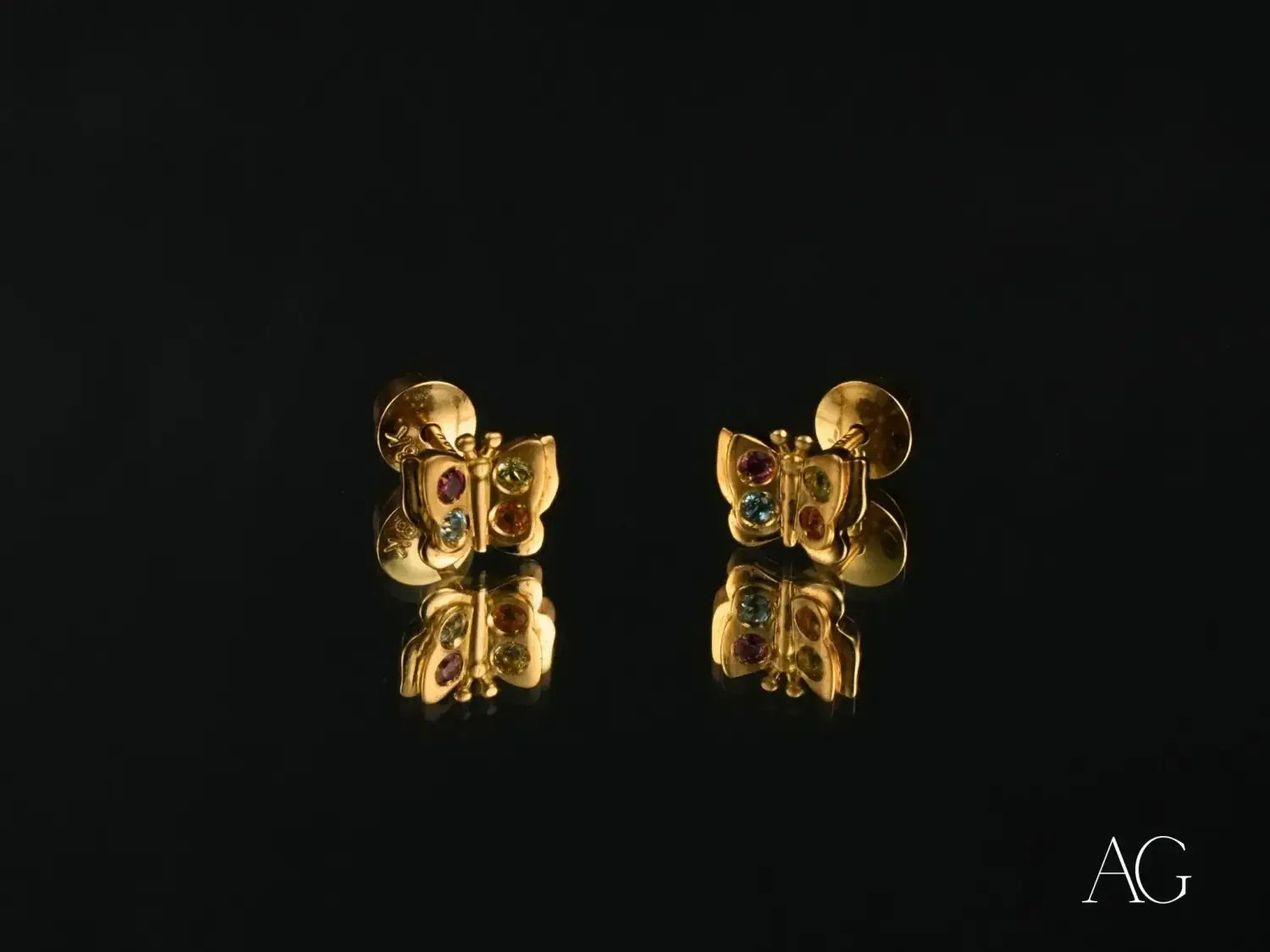 Golden butterfly-shaped stud earrings featuring colorful gemstones showcasing intricate craftsmanship in art gold jewelry at a local Everett jeweler.