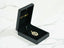 Open black velvet jewelry box showcasing a golden charm boy pendant with religious silhouette