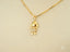Golden charm doll pendant featuring girl design with diamond-studded dress in art gold jewelry style