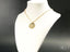 Gold-tone chain necklace with a round, smooth Golden Faith Tudo Posso pendant, art gold jewelry