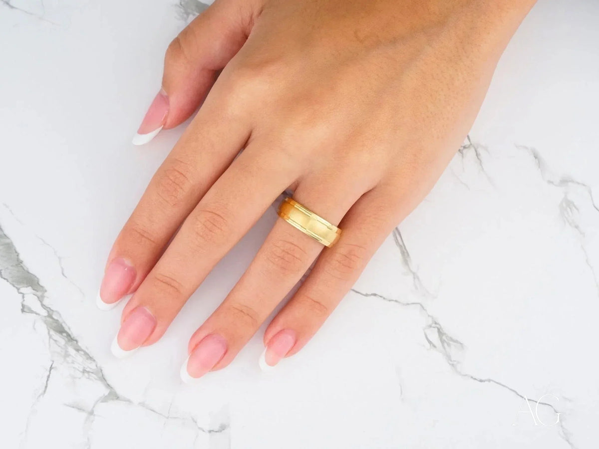 Golden Fortress wedding band: gold-toned ring with textured ridged band on finger