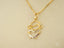Gold-tone necklace featuring a girl-shaped pendant holding a textured heart, a stunning heart doll pendant in art gold jewelry