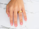 Womans French-manicured hand wearing Golden Meridian gold wedding band