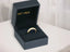 Open dark-colored ring box displaying Golden Trio 18k 3-Tone Hearts Ring with small stones