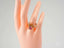 Gold ring with rectangular pink gemstone on mannequin hand, showcasing harmony stone ring in 18k yellow gold art gold jewelry