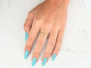 Hand with turquoise nails wearing radiant love gold heart ring from 4H’s Collection