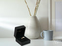 Heart’s Glow Ring in open black velvet box with radiant 18k gold gem