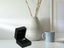 Open black velvet ring box showcasing the Heart’s Glow Ring with a dangling heart charm in radiant 18k gold