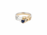 Front view of two-tone gold ring with two sculpted hands united, cradling sapphire and diamond accents