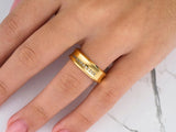 Side view of gold wedding band with wavy curved edges and central diamond row