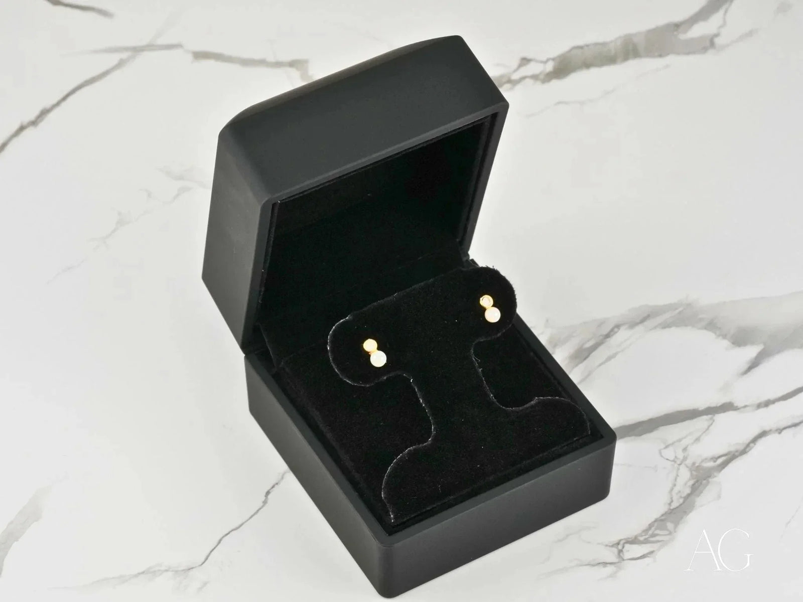 Open black jewelry box with Lustrous Harmony 18K gold pearl drop earrings