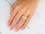 Close-up of a woman’s hand wearing a majestic weave gold wedding band from Art Gold Jewelry