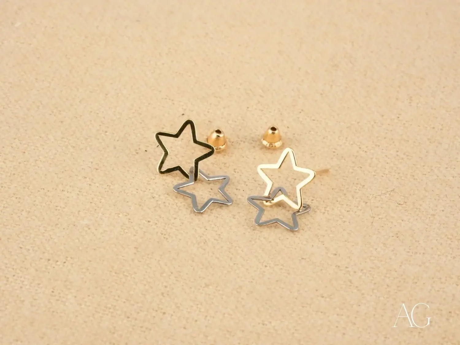 A pair of minimalist star-shaped stud earrings in black, silver, and gold tones with a layered design showcasing fine jewelry craftsmanship in gold jewelry care tips.