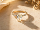 A radiant oval-cut diamond engagement ring set in a 14k gold band with pavé diamonds along the sides, featuring an engraved ’arigold750 signature’ inscription.