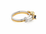 Detailed side view of sculpted hands and sapphire setting on two-tone gold band