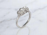 Side profile view of white gold three-stone diamond ring showing raised setting