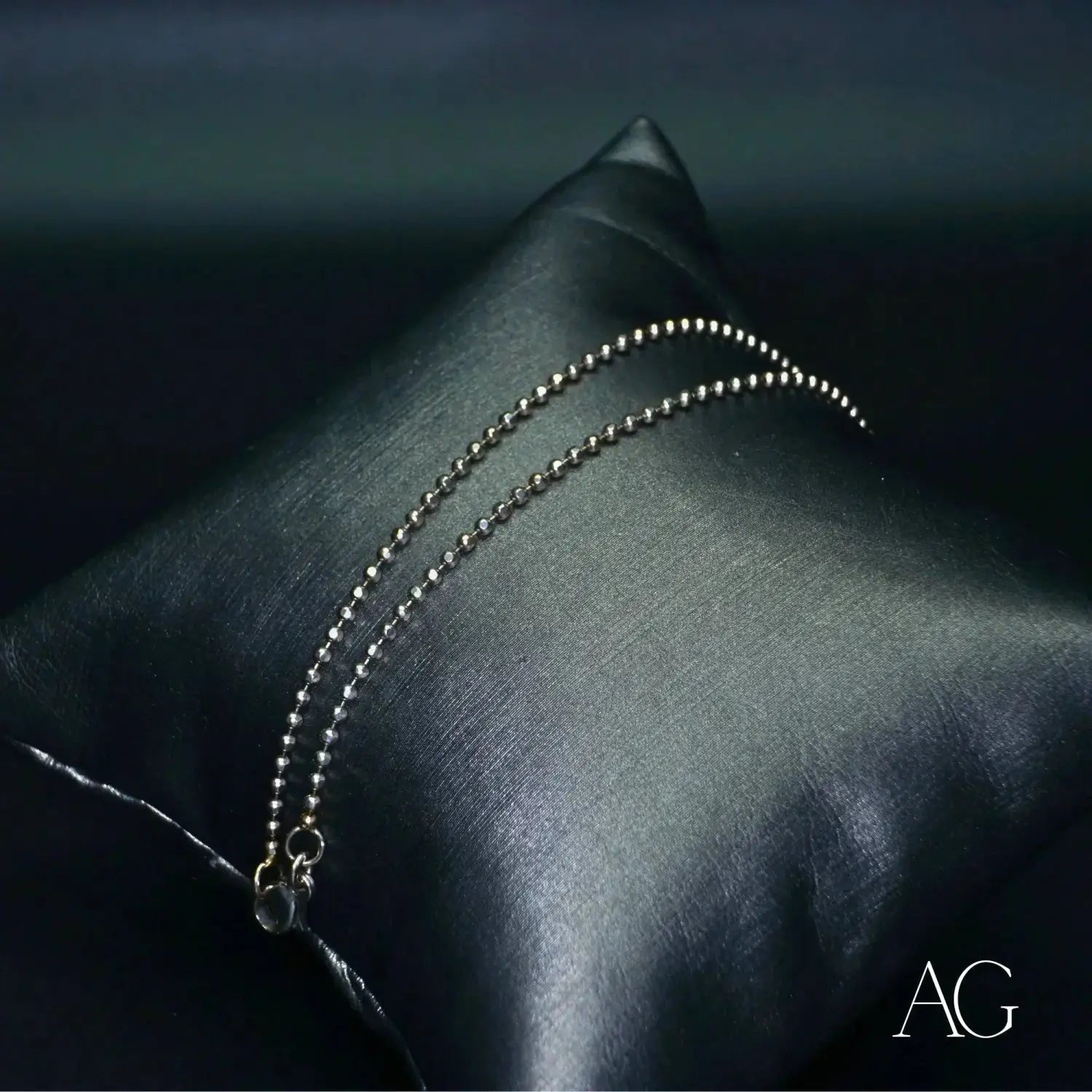 Exquisite silver ball chain anklet on black satin pillow, art gold jewelry.