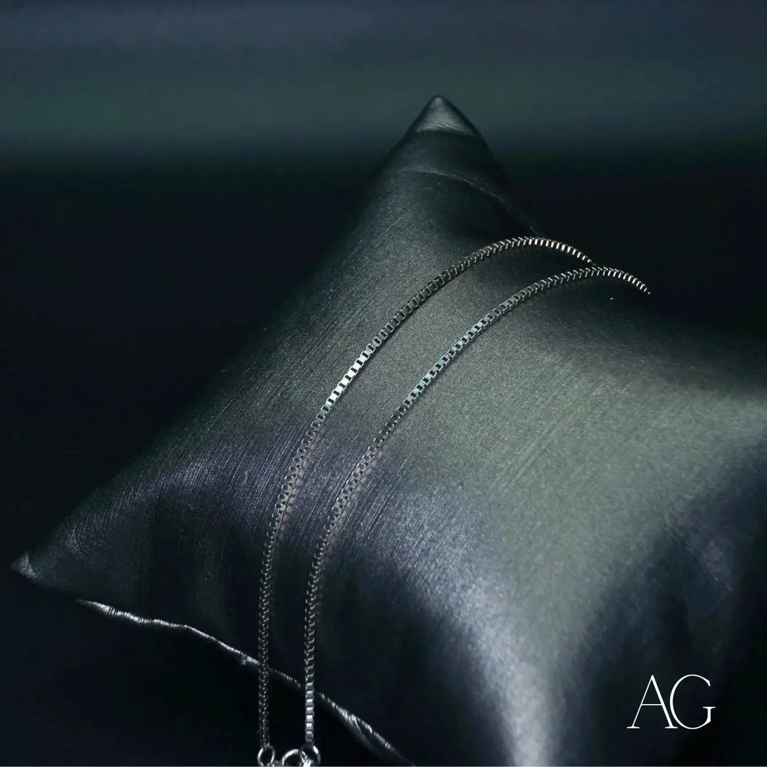 silver box chain necklace displayed on a black satin pillow complements art gold jewelry and stunning 18k gold designs bridging timeless elegance and modern art