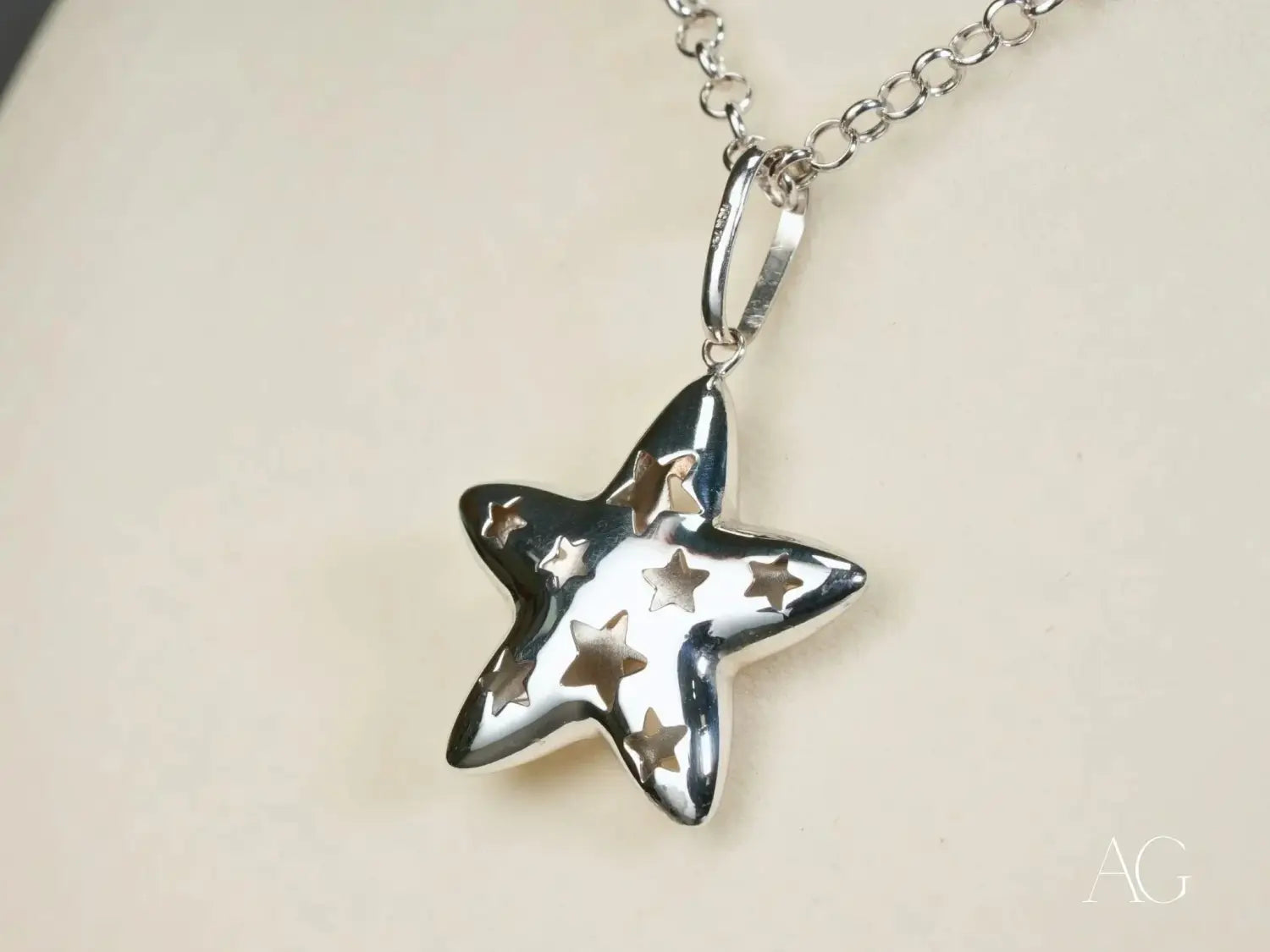 silver star-shaped pendant necklace with polished metallic finish and intricate cut-out stars, illustrating fine jewelry craftsmanship in an article about the importance of jewelry care tips and maintenance for handmade gold masterpieces