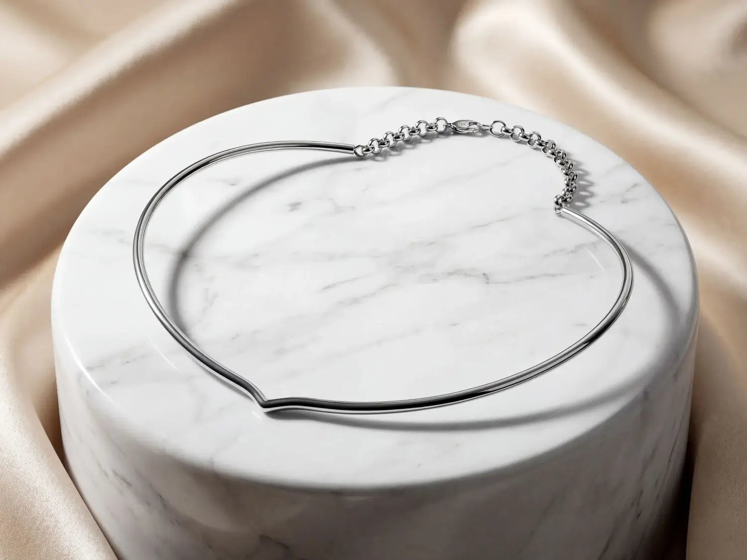 Silver-toned minimalist choker necklace with a sleek continuous band and delicate chain clasp displayed in an article about how to clean gold jewelry and maintain fine jewelry including 18k gold pieces.