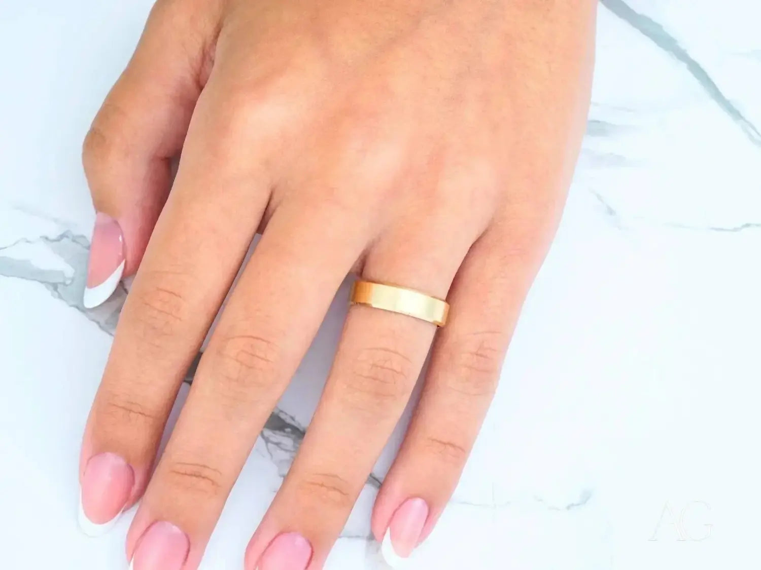A collection of gold jewelry featuring 18k gold wedding bands with various designs including a pink opal ring.