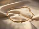 A sleek, gold-toned choker necklace with a minimalist design and delicate chain clasp.