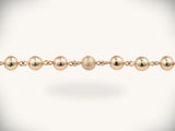 Solid gold rosary necklace with gold-toned ball chain and emerald diamond cross