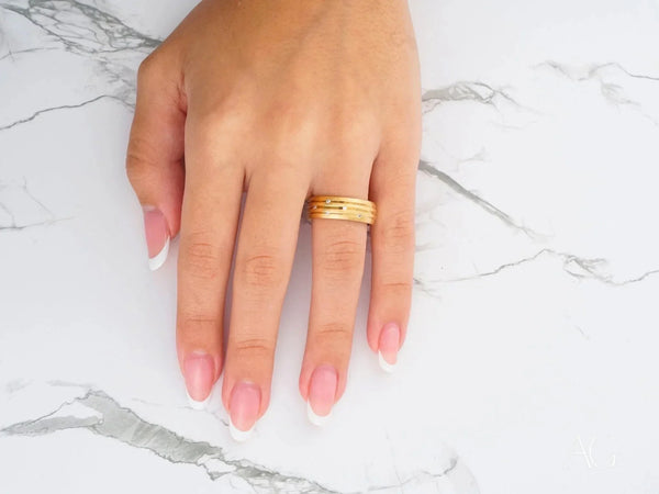Stellar Strands gold wedding band with sleek gold lines on French manicure finger