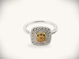 A stunning yellow diamond ring with a square-cut center stone surrounded by two concentric rows of sparkling white diamonds, set in a sleek silver band featuring a twisted design.