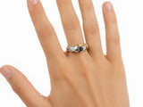 Three-quarter view of two-tone gold ring with clasped hands, sapphire and diamond cuff details