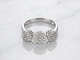 Three-stone diamond cluster ring, top-down view of three circular diamond clusters and diamond shoulders