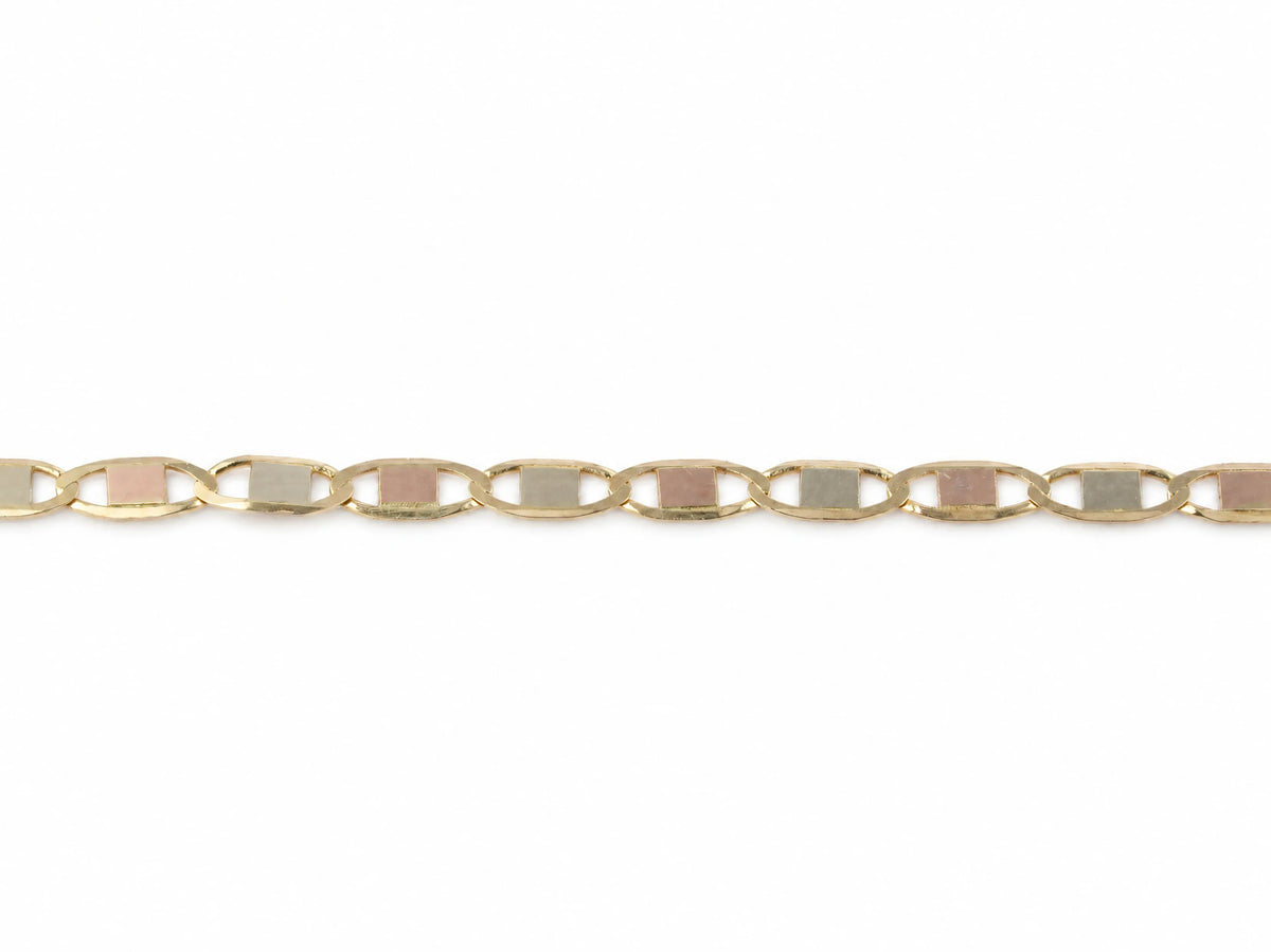 Piastrine chain laid flat, roughly ten yellow gold oval links with plates alternating white and rose gold, both ends cropped by the frame