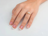 Hand with French-tipped nails wearing Twist of Brilliance twisted band engagement ring featuring diamond focal point