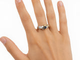 Three-quarter view of two-tone gold ring with clasped hands, sapphire and diamond cuff details