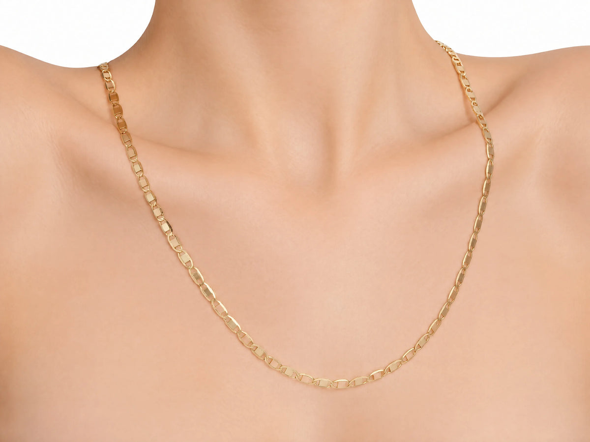 14K gold piastrine chain worn alone on a mannequin bust, resting below the collarbone